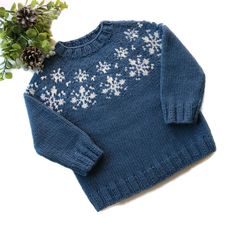 a blue sweater with white snowflakes on it and a flower in the middle