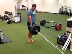 a man holding a barbell in a gym with other equipment on the floor behind him