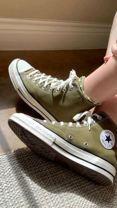 a woman's legs with green converse sneakers on