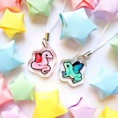 two glass pendants with colorful designs on them sitting next to star shaped confetti