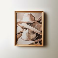 a painting of two hats hanging on the wall above a framed photograph in a wooden frame