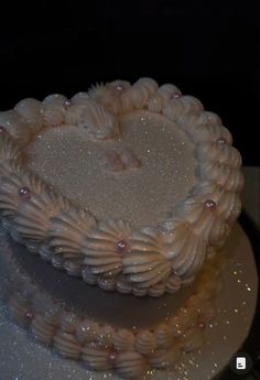 a heart shaped cake on a plate with sparkles in the middle and white frosting