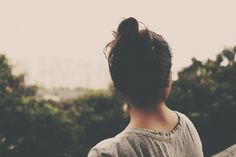 the back of a woman's head, with an image of trees in the background