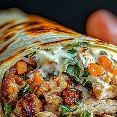 a close up of a burrito with meat and veggies