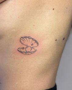 a woman's stomach with a small shell tattoo on her left side ribcage