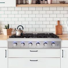 a stove top oven sitting inside of a kitchen next to white cupboards and counter tops