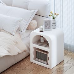 a bed with white sheets and pillows on top of it next to a night stand