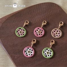 four different colored charms sitting on top of a wooden table next to a brown cloth