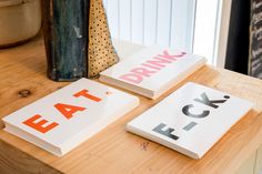 three cards that say eat, drink and lock on a wooden table next to a potted plant