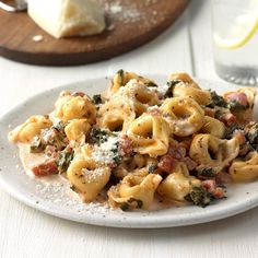 pasta with ham and spinach on a plate next to a slice of lemon wedge