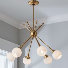 a chandelier with five lights hanging from it's ceiling in a room