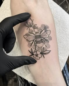 a woman's arm with a tattoo on it that has a bee and flowers