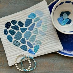 a blue and white table setting with a heart shaped piece of cloth next to it