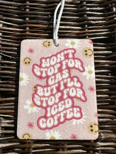 a pink square ornament hanging from a wicker basket with words written on it