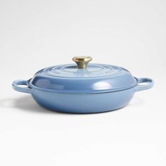 a blue casserole dish with a gold handle on a white background, the lid is slightly open