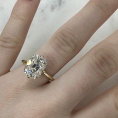 a woman's hand with a diamond ring on top of her finger and the other hand holding an engagement ring