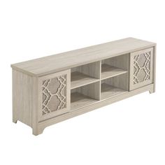 a white wooden entertainment center with intricate carvings on the doors and shelves, along with an open shelf