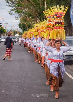 a group of people that are walking down the street with some fruit on their heads