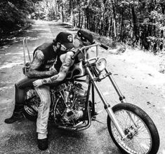 black and white photograph of a man on a motorcycle kissing another man's face