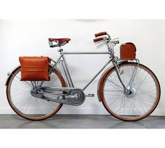 an orange and silver bicycle parked next to a wall with a clock on it's side