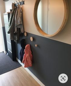 a coat rack with coats hanging on it next to a wall mirror and coat rack