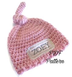 a pink crocheted hat with the word zoo on it and a white background