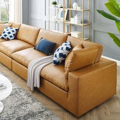 a tan leather couch with blue and white pillows