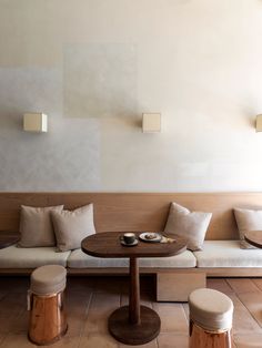 a living room filled with lots of furniture next to a wooden table and two stools