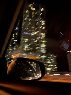 a car's side view mirror with the city lights in the background