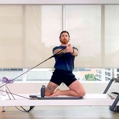 a man is doing exercises on a rowing machine in a room with windows and blinds