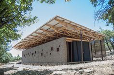 a small building made out of concrete and wood with a roof over the entrance to it