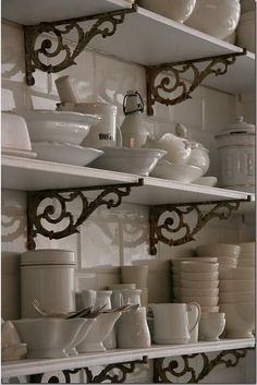 the shelves are filled with white dishes and cups on them, along with other kitchen items