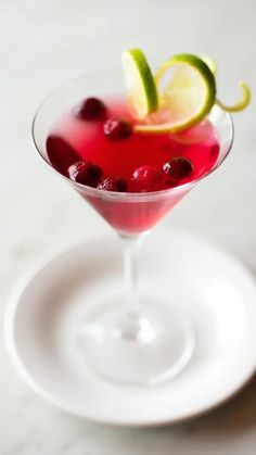 a glass filled with red liquid and garnished with lemon wedges on a white plate