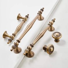 an assortment of antique style handles and knobs on a white surface with one door handle in the middle