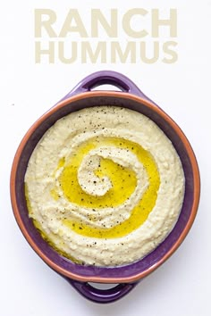 a purple bowl filled with hummus on top of a white table