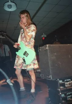 a man standing in front of a green guitar