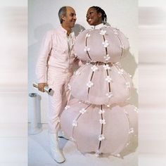 a man and woman standing next to each other in front of a large pink cake