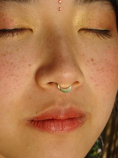 a close up of a woman with her eyes closed and nose piercing in the middle