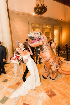 the bride and groom are posing with an inflatable dinosaur