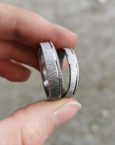 someone is holding two wedding bands in their hand and the ring has been made out of silver