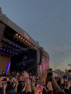 a large group of people standing on top of a stage with their hands in the air