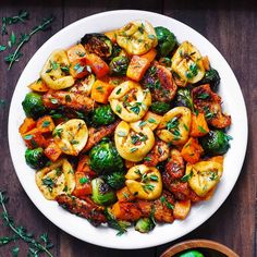 a white plate topped with brussel sprouts and other vegetables on top of a wooden table