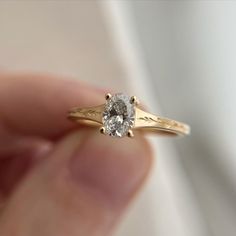 a close up of a person's hand holding a ring with a diamond in it