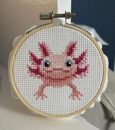 a cross stitch pattern with an image of a pink crab on it's face