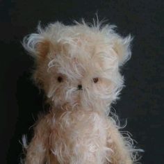 a teddy bear with white hair sitting in front of a black background