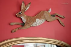 a rabbit is hanging on the wall next to a mirror