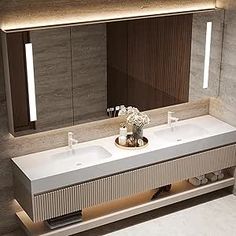 a bathroom vanity with two sinks and lights on the mirror above it is illuminated by recessed lighting