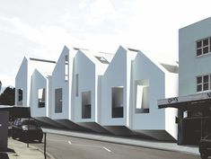 a white building on the side of a road with cars parked in front of it