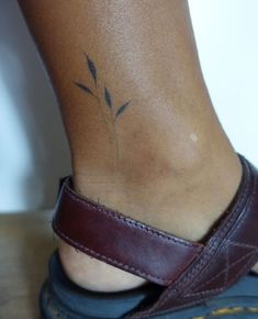 a woman's foot with a small tattoo on the side of her leg and an ankle strap