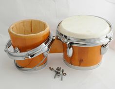 two wooden drums are sitting next to each other on a white surface with screws